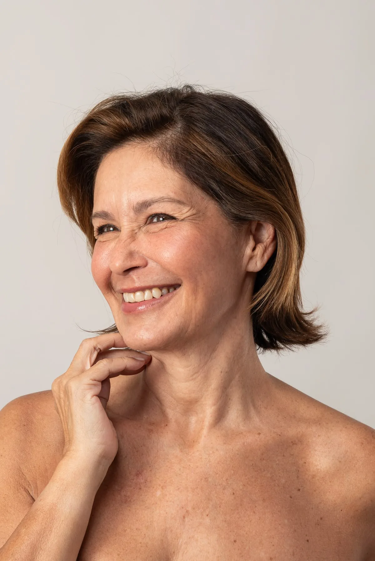 Mulher madura sorrindo com a mão no pescoço