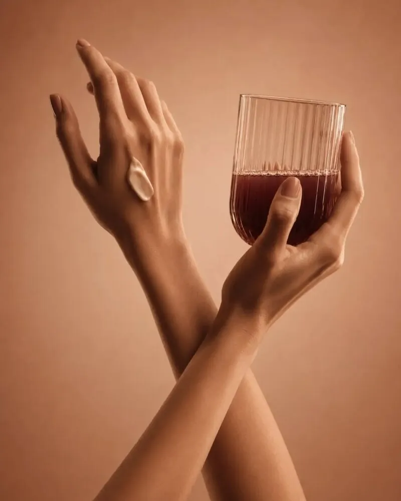 Mãos elegantes segurando uma taça sobre fundo terracota