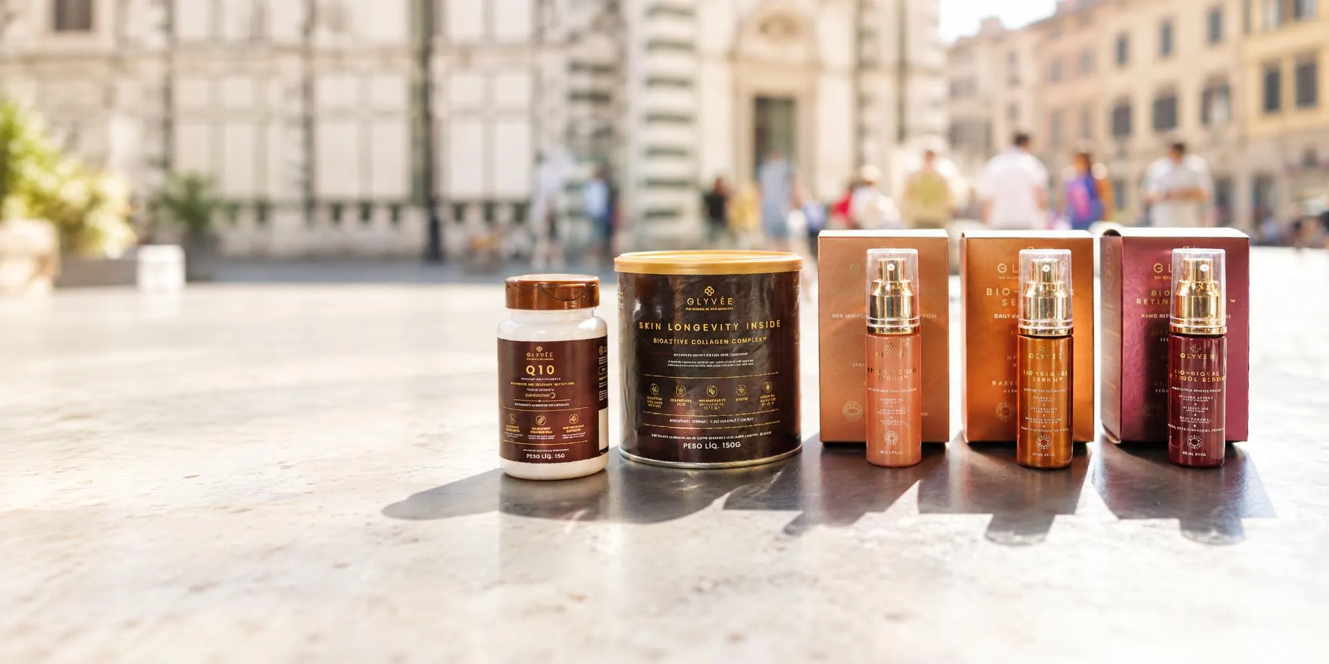 Os cinco produtos Glyvée juntos: Q10, Skin Longevity Inside e os três séruns, sobre uma mesa ao sol
